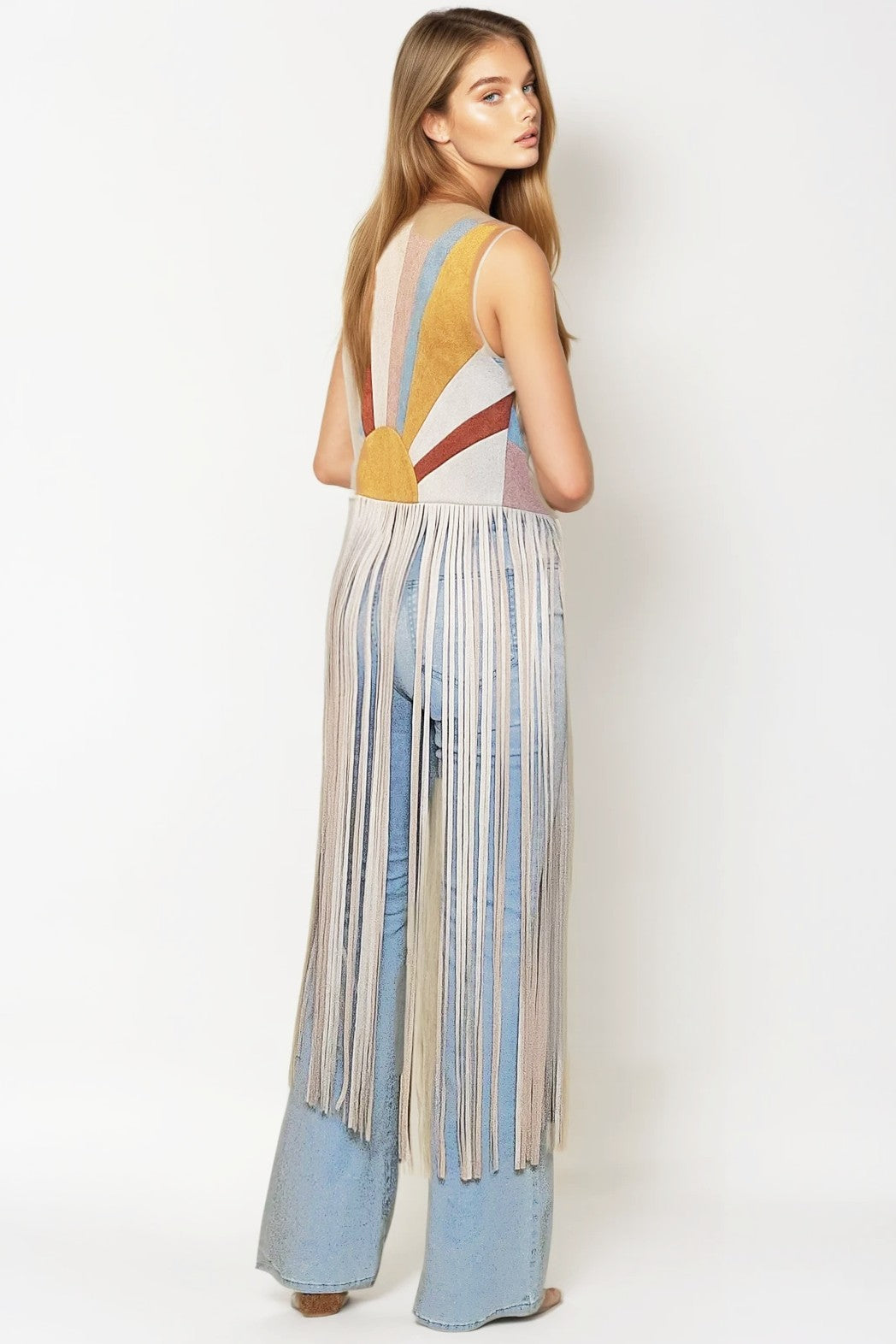 Back view of the ivory faux suede sunburst vest with long fringe, worn over wide leg jeans
